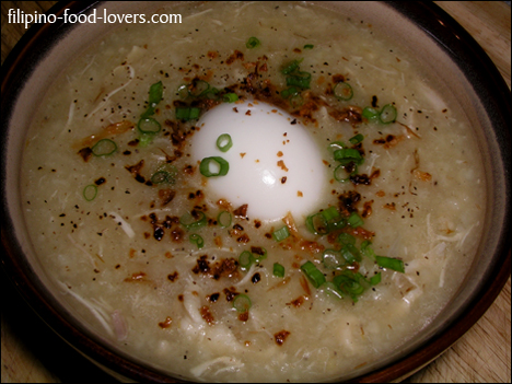 Arroz caldo in a bowl with egg, green onion and roasted garlic (top view)